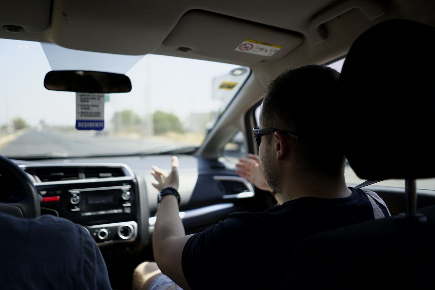 View from the back seat of an instructor gesturing towards the road while a student drives