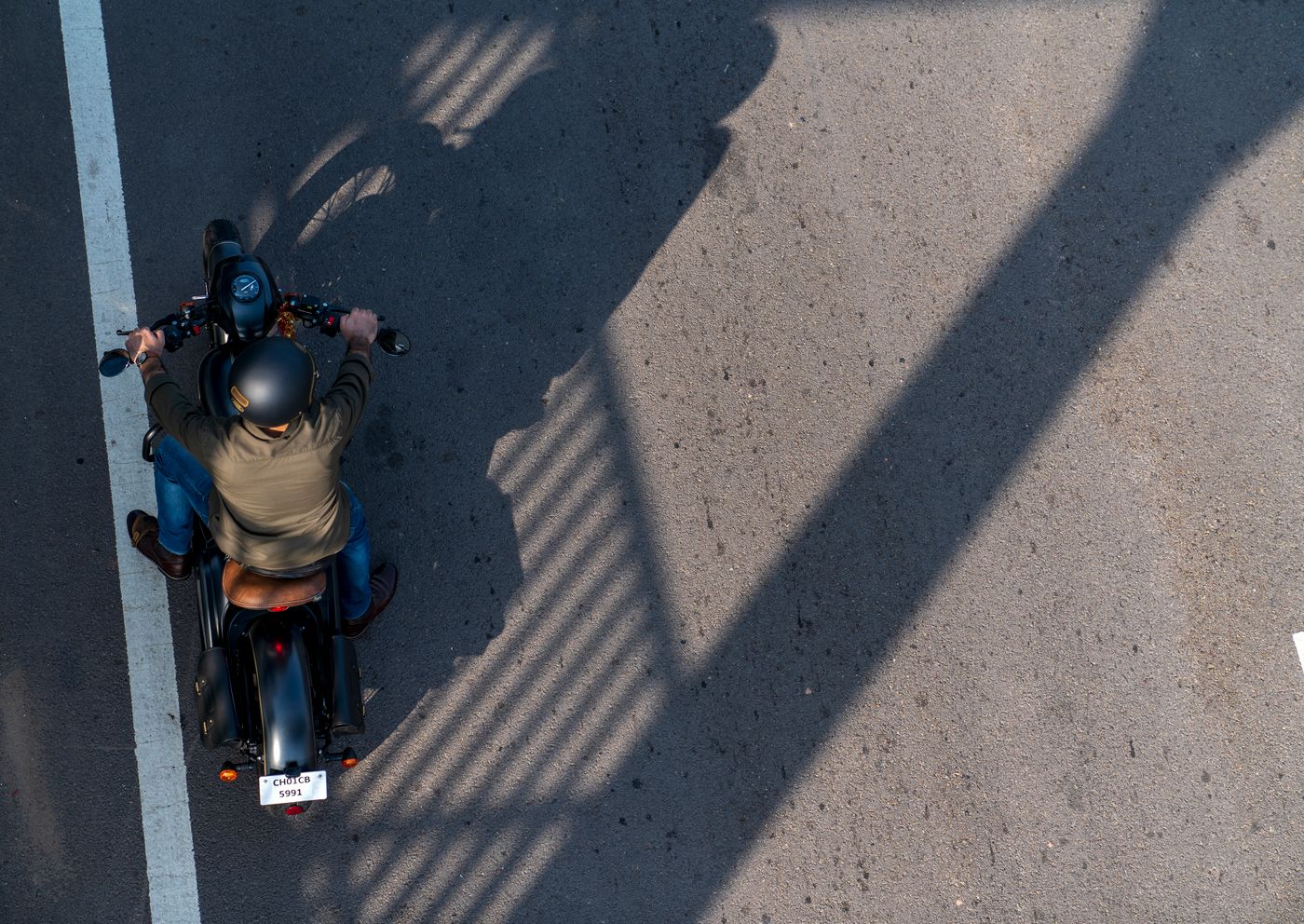 Overhead view of a helmeted rider on a motorcycle crossing a lane marking